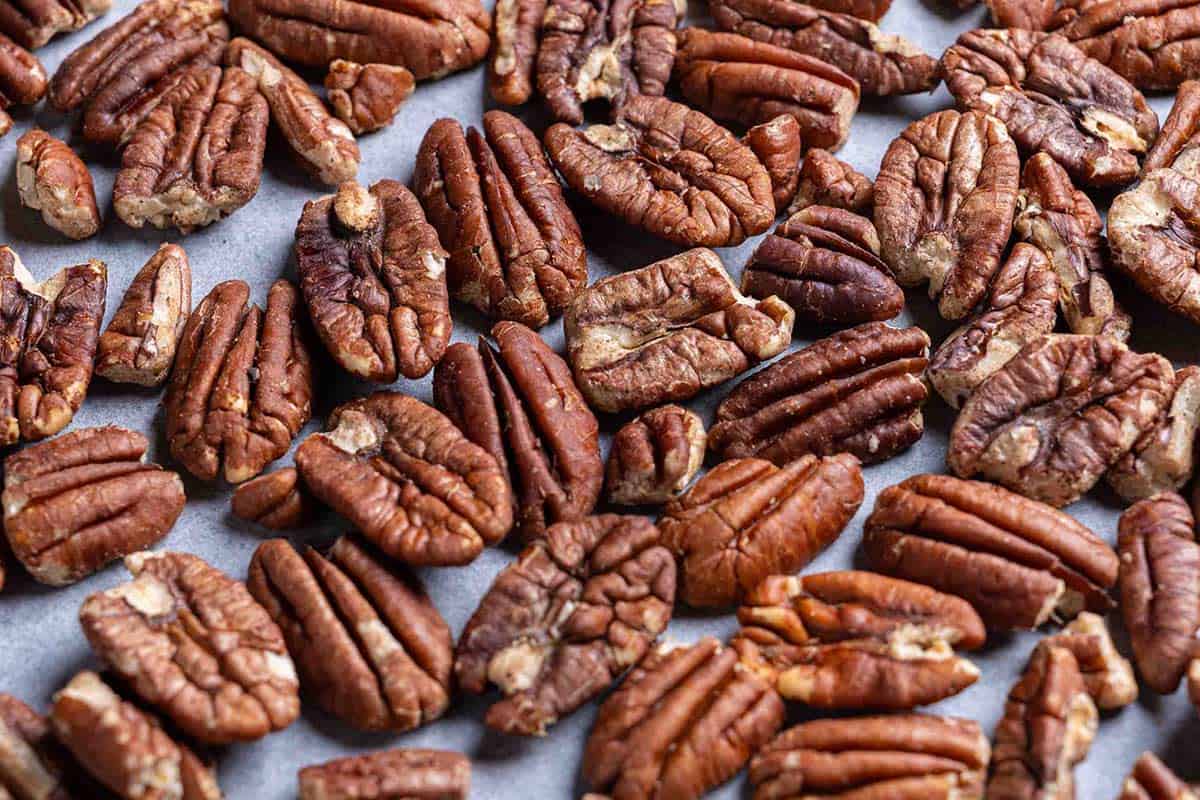 Toasted pecans spread out in a baking tray.