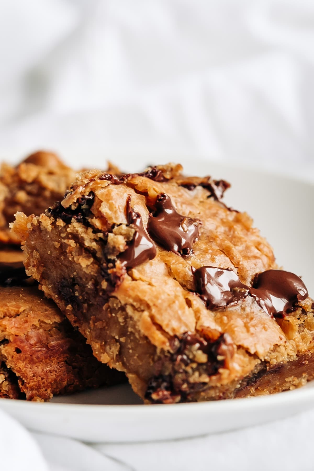 A piece of chickpea banana blondies with melted chocolate chips on a white plate