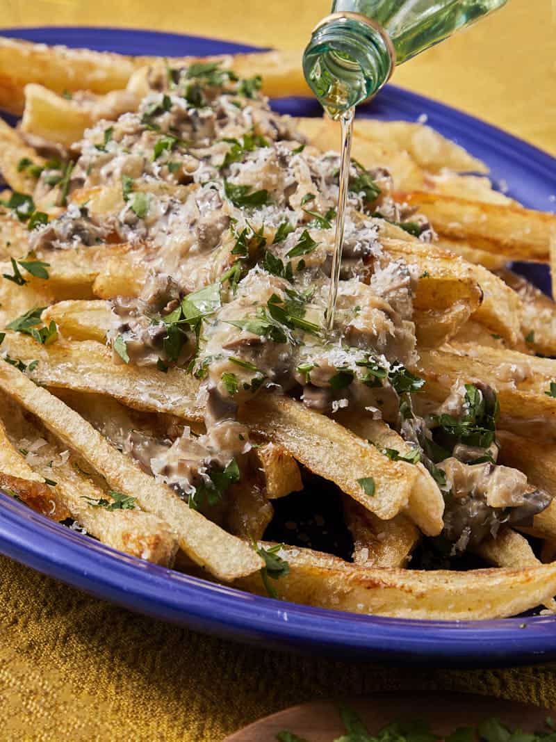 crispy chips with a blue bowl topped with mushroom truffle sauce with parmesan