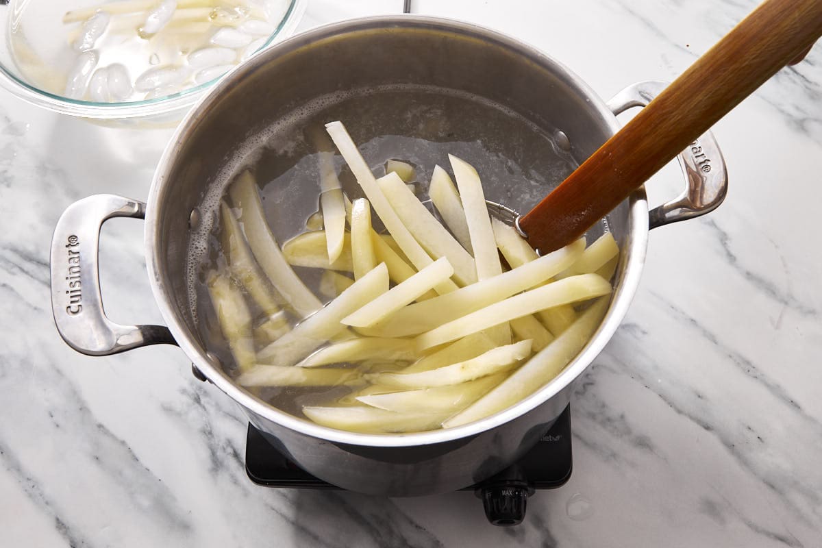 chopped potatoe fries uncooked in a pot being boiled