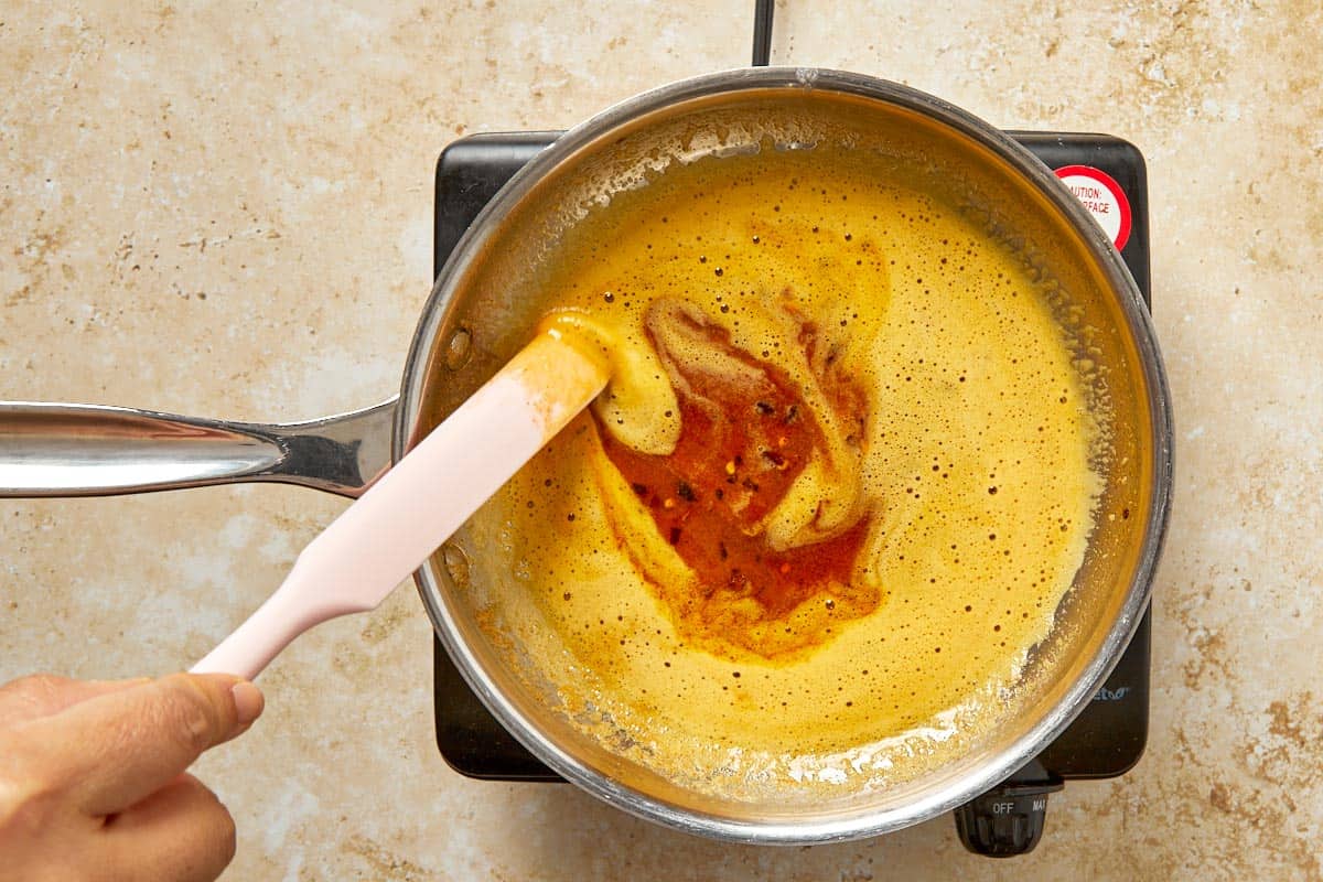 Melting butter with paprika and chili flakes in a pan.