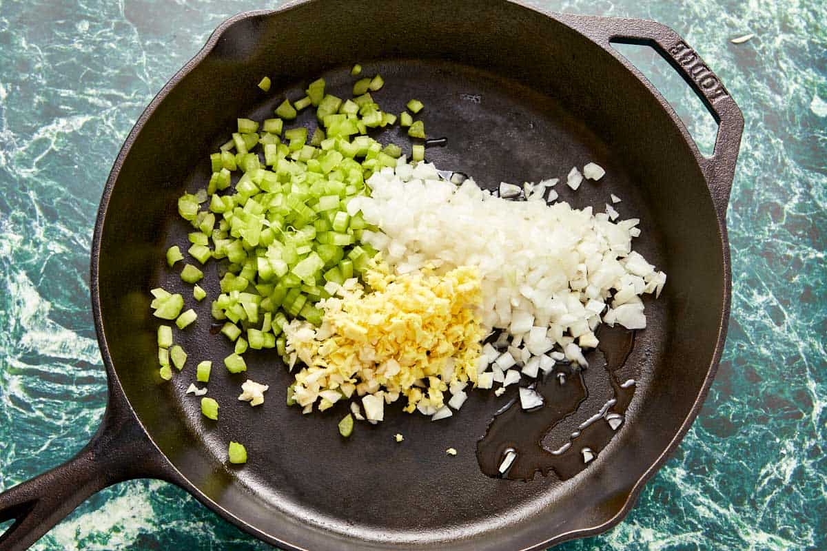 A skillet filled with sautéing onions, green onions, and garlic in sesame oil.