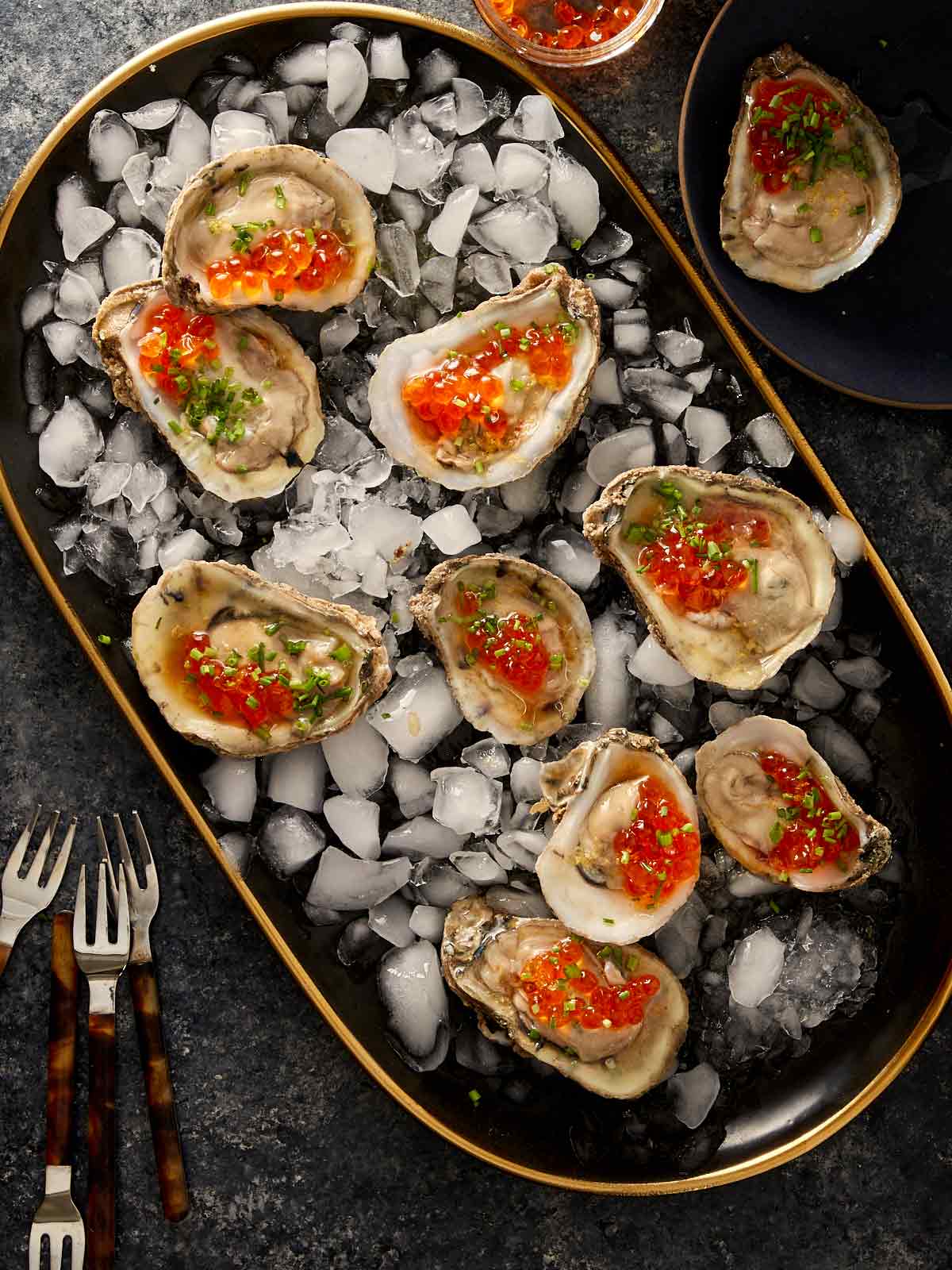 Oysters on the half shell with salmon roe and chives served on ice.