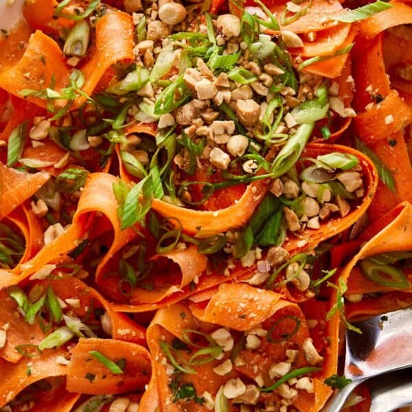carrot salad with peanuts on top and a spoon on the side