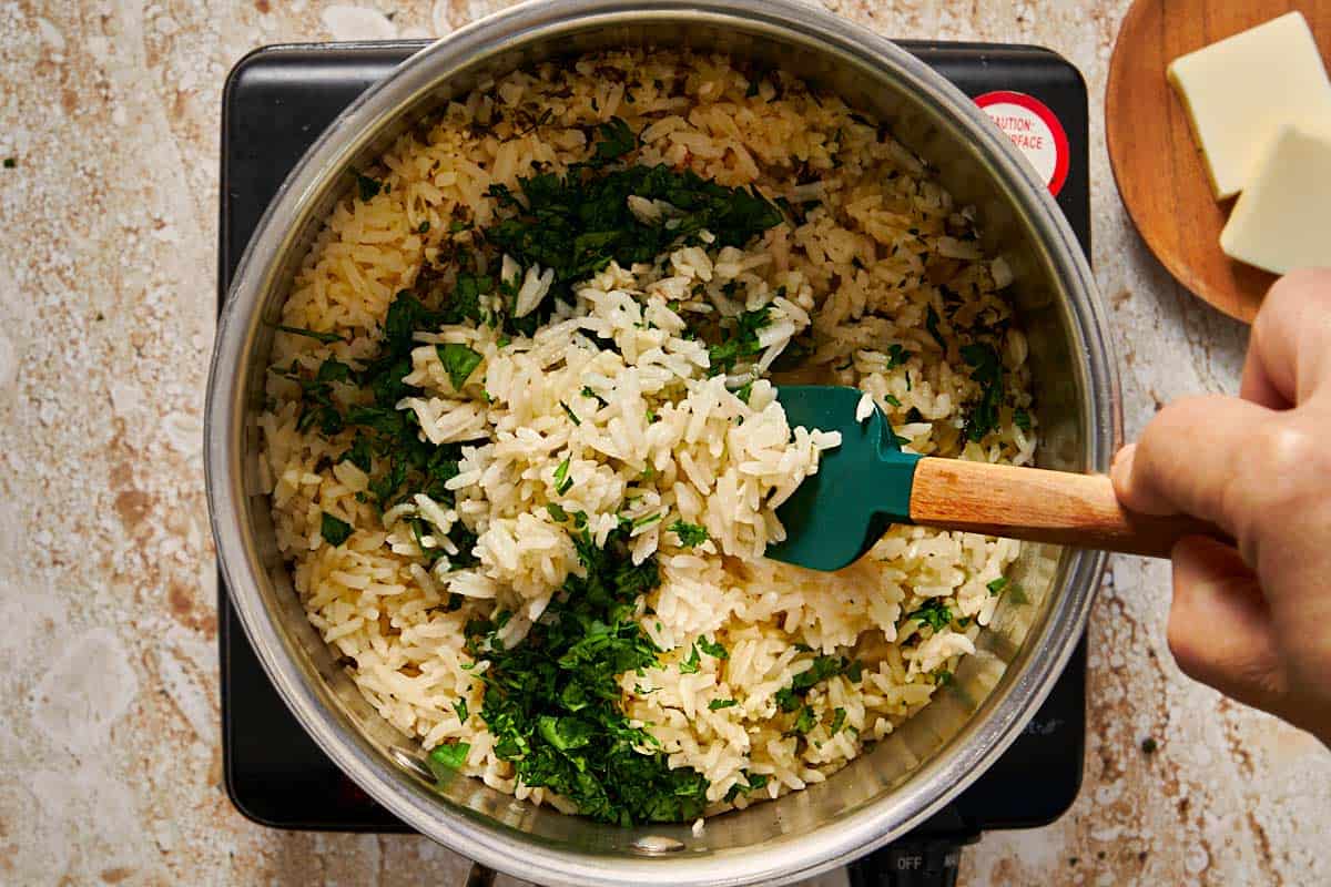 rice being cooked in a pot having fresh parsley poured in