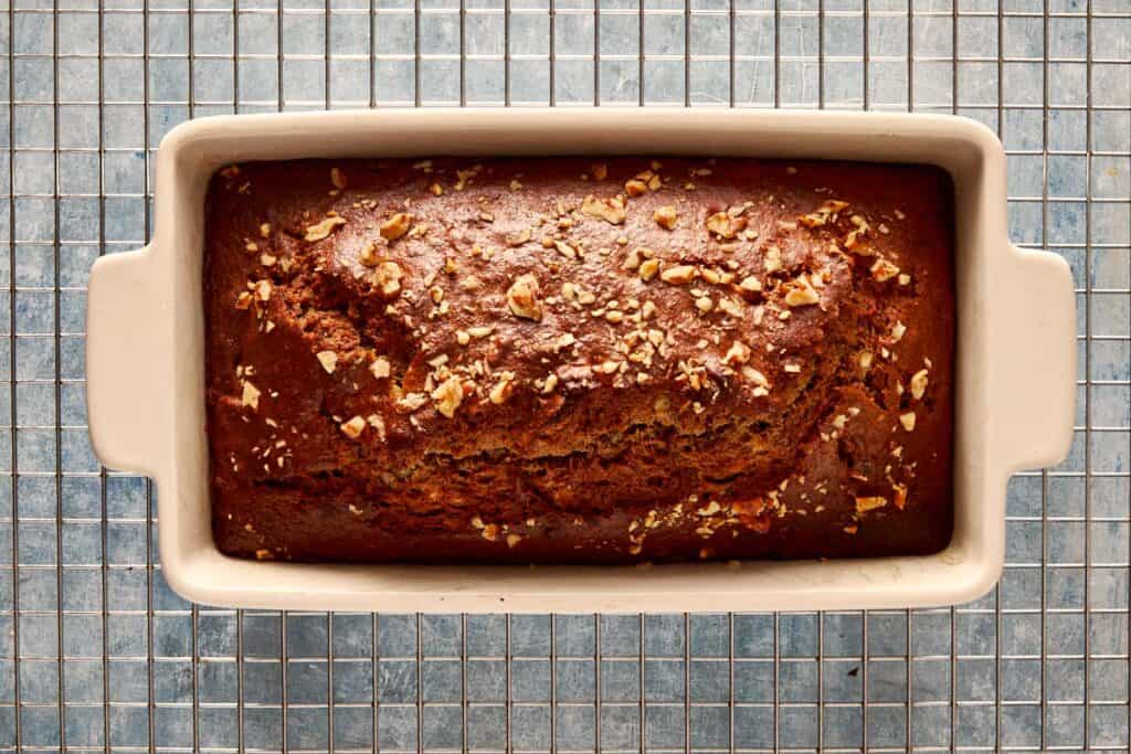 a top down view of banana bread baked in a rectangular loaf pan resting on a wire tray cooling
