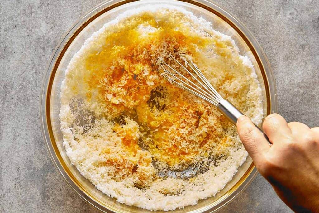 a top down view of a glass bowl with a whisk mixing the dry ingredients and milk