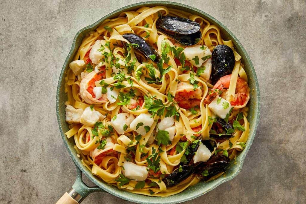 a top down view of seafood and pasta mixed together in a pan