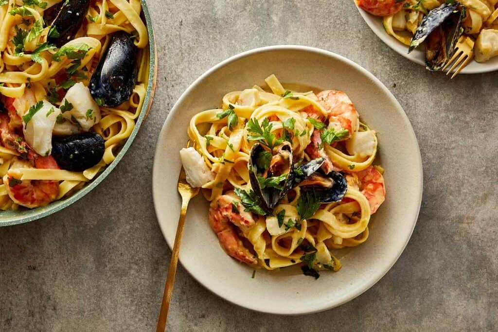 a top down view of a white plate full of pasta and seafood