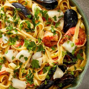 a top down view of a creamy seafood pasta dish in a green pan