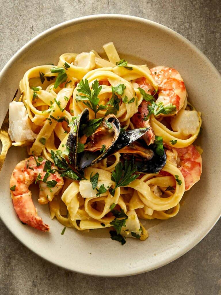 a white plate full of seafood with pasta and seafood