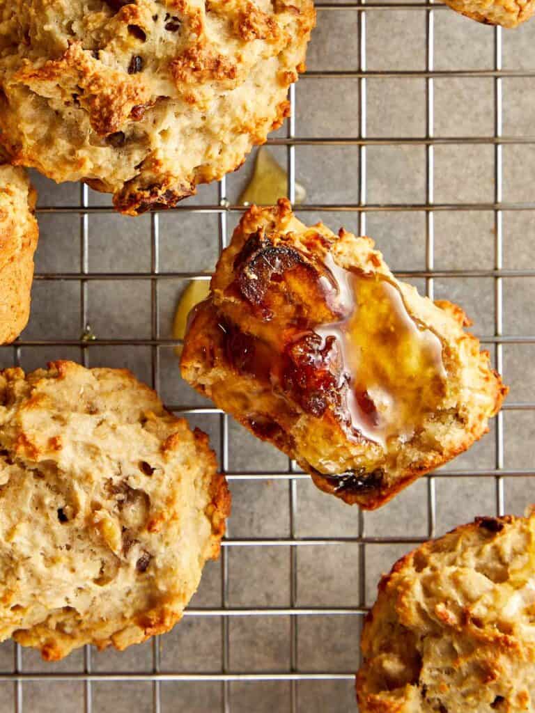 a collection of muffins sitting spaced out on a wire rack cooling close up shot showing honey glazed over half a muffin