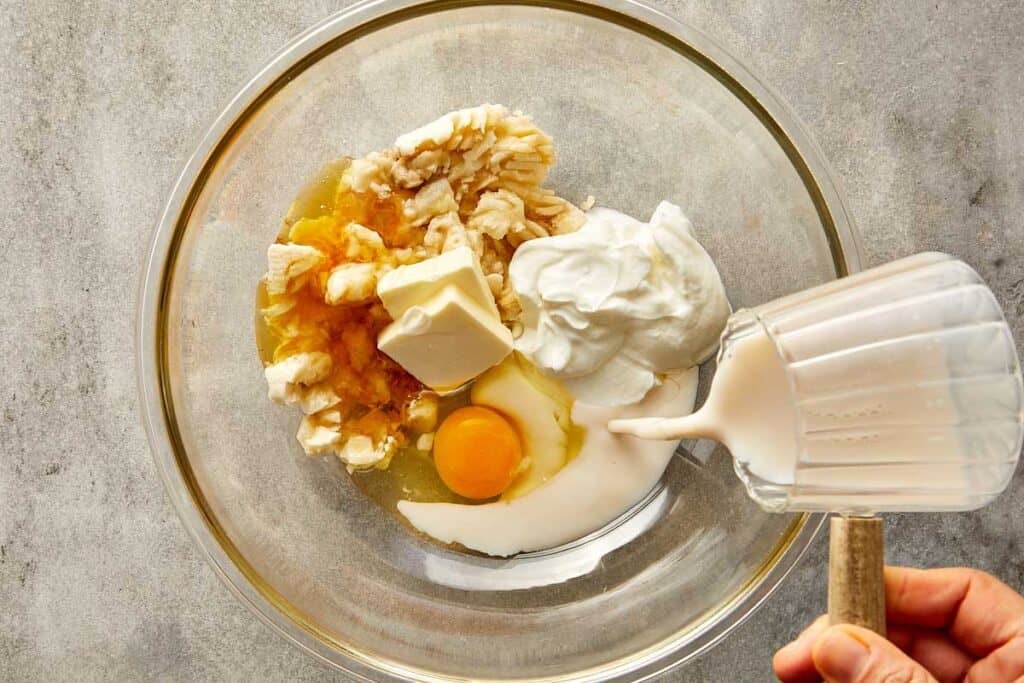 a top down photo of a glass mixing bowl with egg and milk butter and vanilla in it.