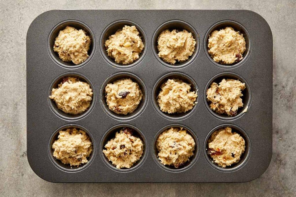 a top down image of raw muffin mix inside each muffin tray ready to be placed in the oven