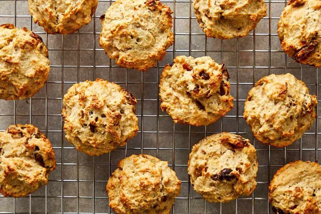 a collection of muffins sitting spaced out on a wire rack cooling