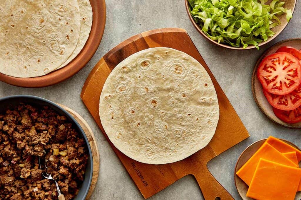 a top down view of a wrap on top of a wooden board sitting on a kitchen bench, the wrap is empty
