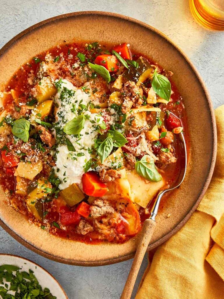top overview of lasagna soup served with ricotta and parmesan cheese and topped with basil and parsely.