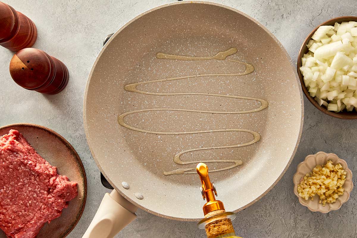 top overview of beige pan being drizzle with olive oil