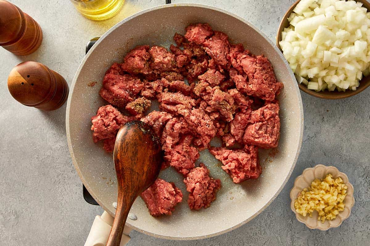 top overview of beef being cooked in a beige pan