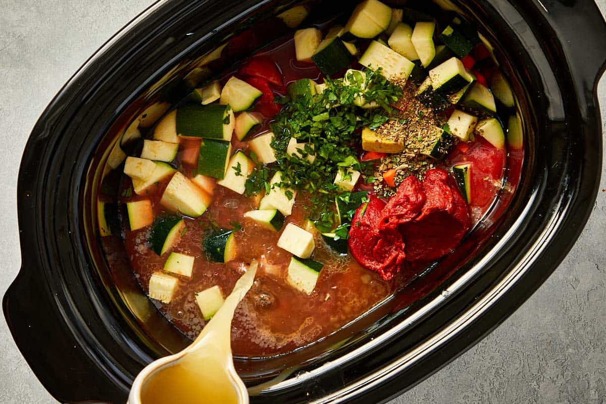 top overview of chicken stock being pour into the slowcooker