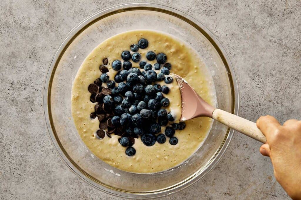 Gently folding fresh blueberries and chocolate chips into thick pancake batter to keep blueberry chocolate chip pancakes light and fluffy.