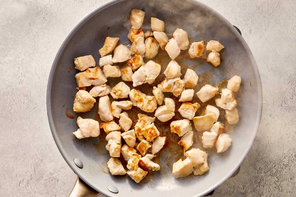 a top down view of a frying pan with chicken browning in the pan