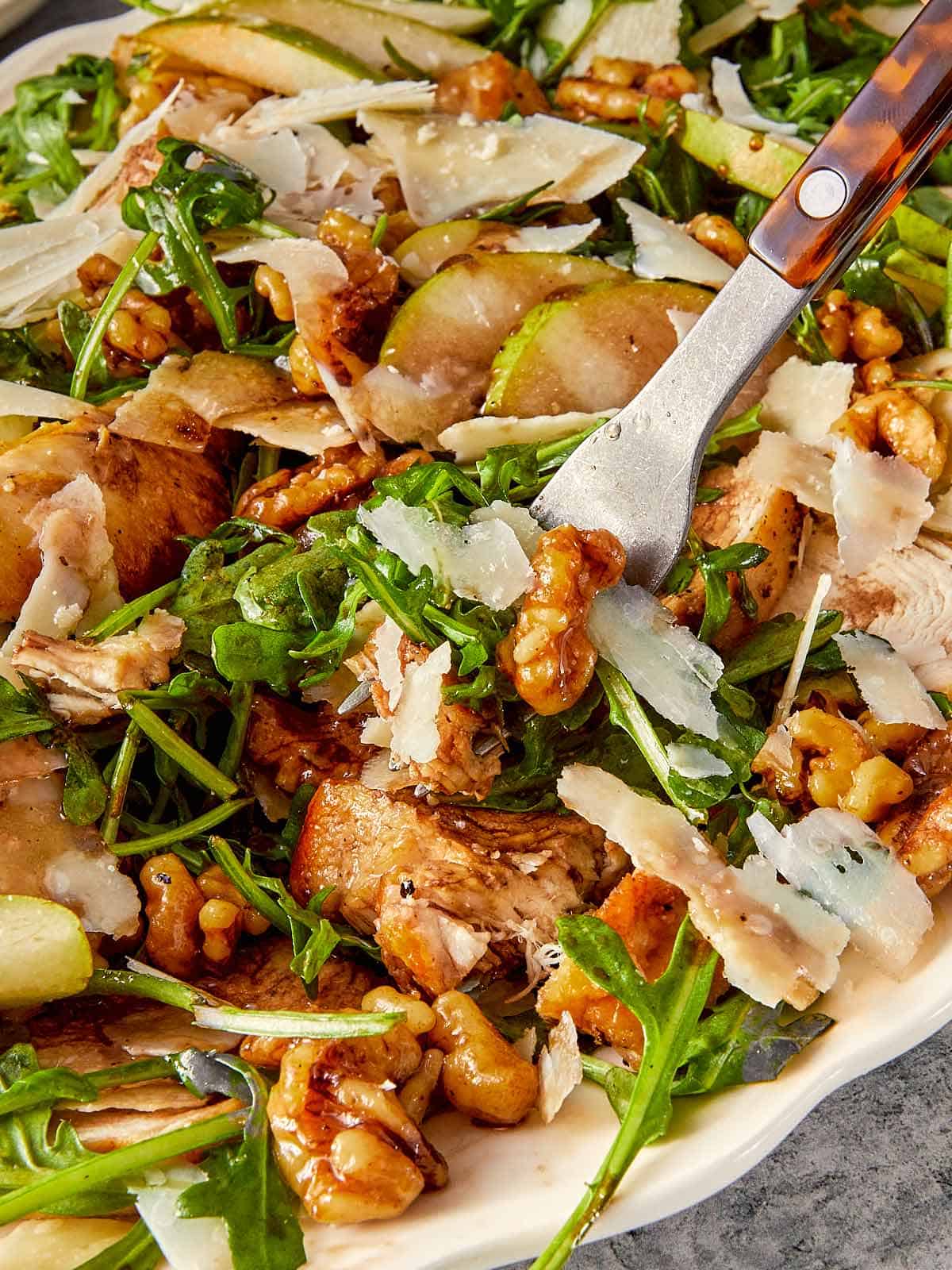 close up of a fork with arugula salad in a gray surface 