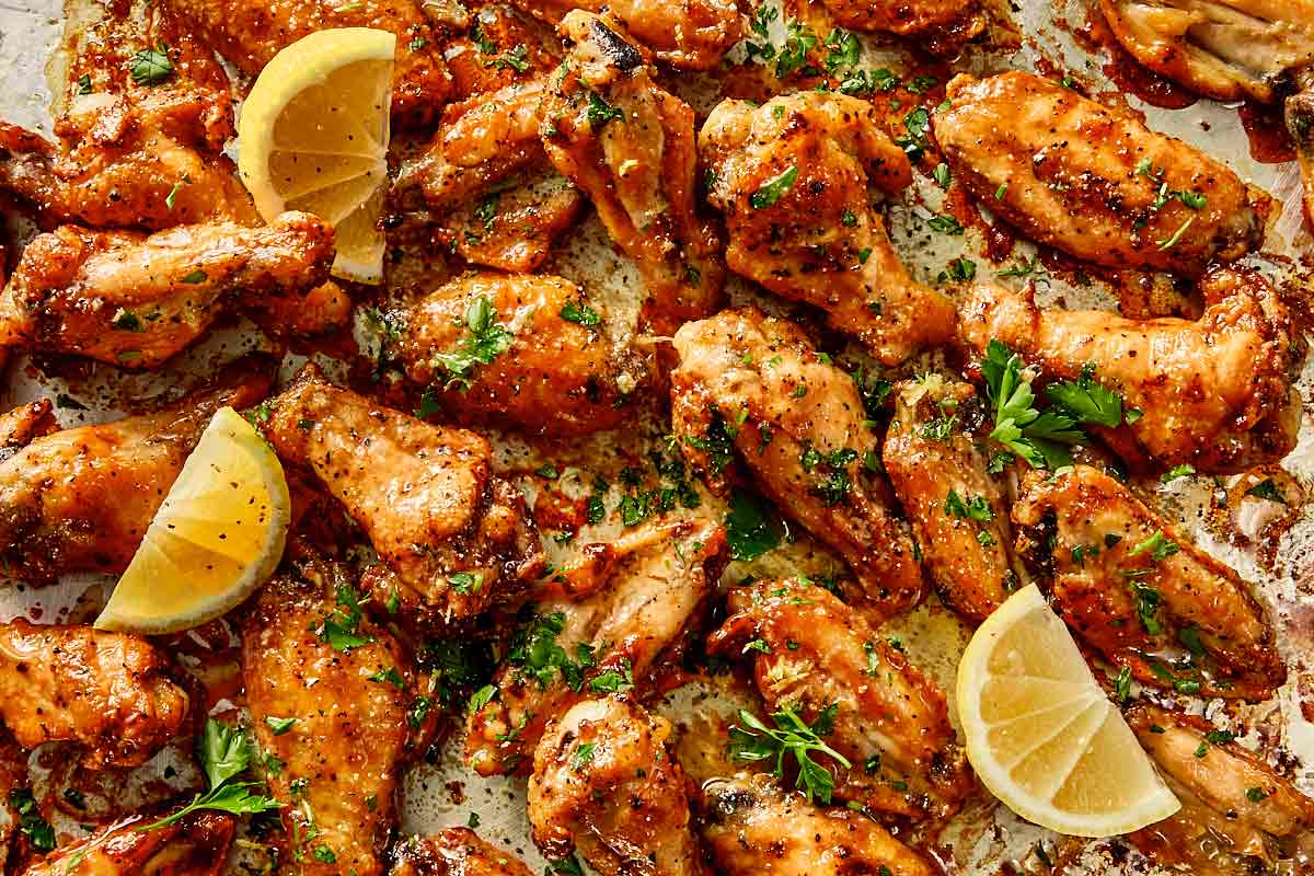 Crispy lemon pepper chicken wings coated in buttery sauce, finished with fresh parsley and lemon wedges ready to serve