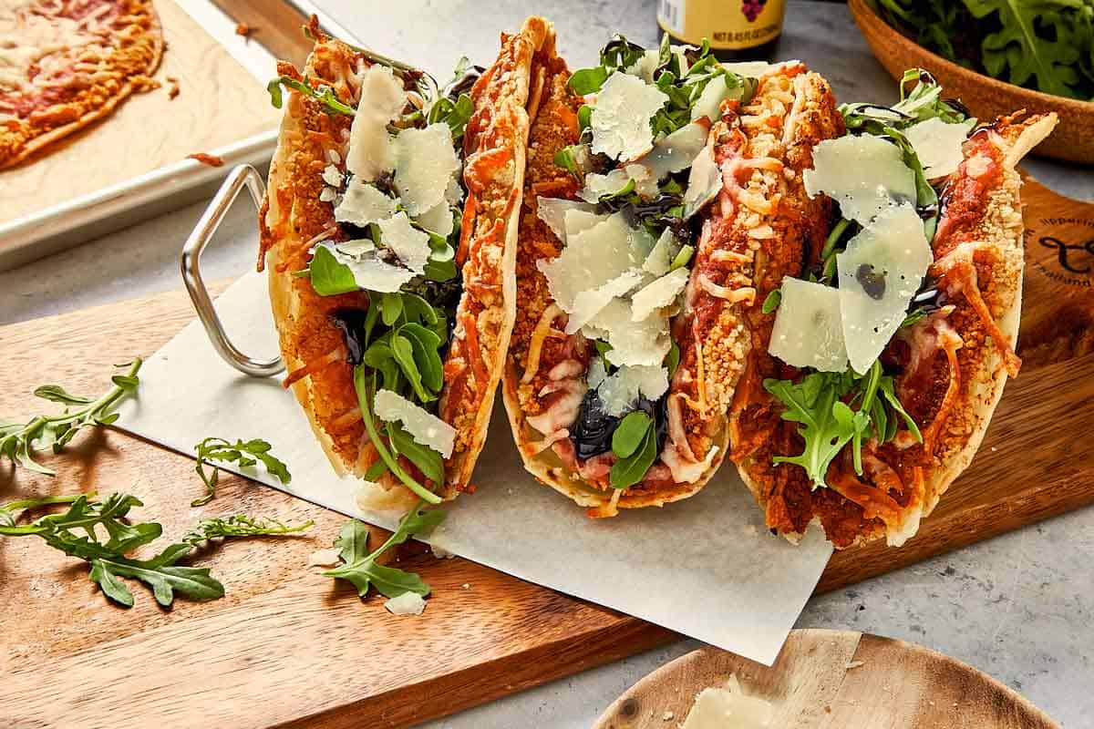 Chicken parm smashed tacos assembled with arugula and toppings