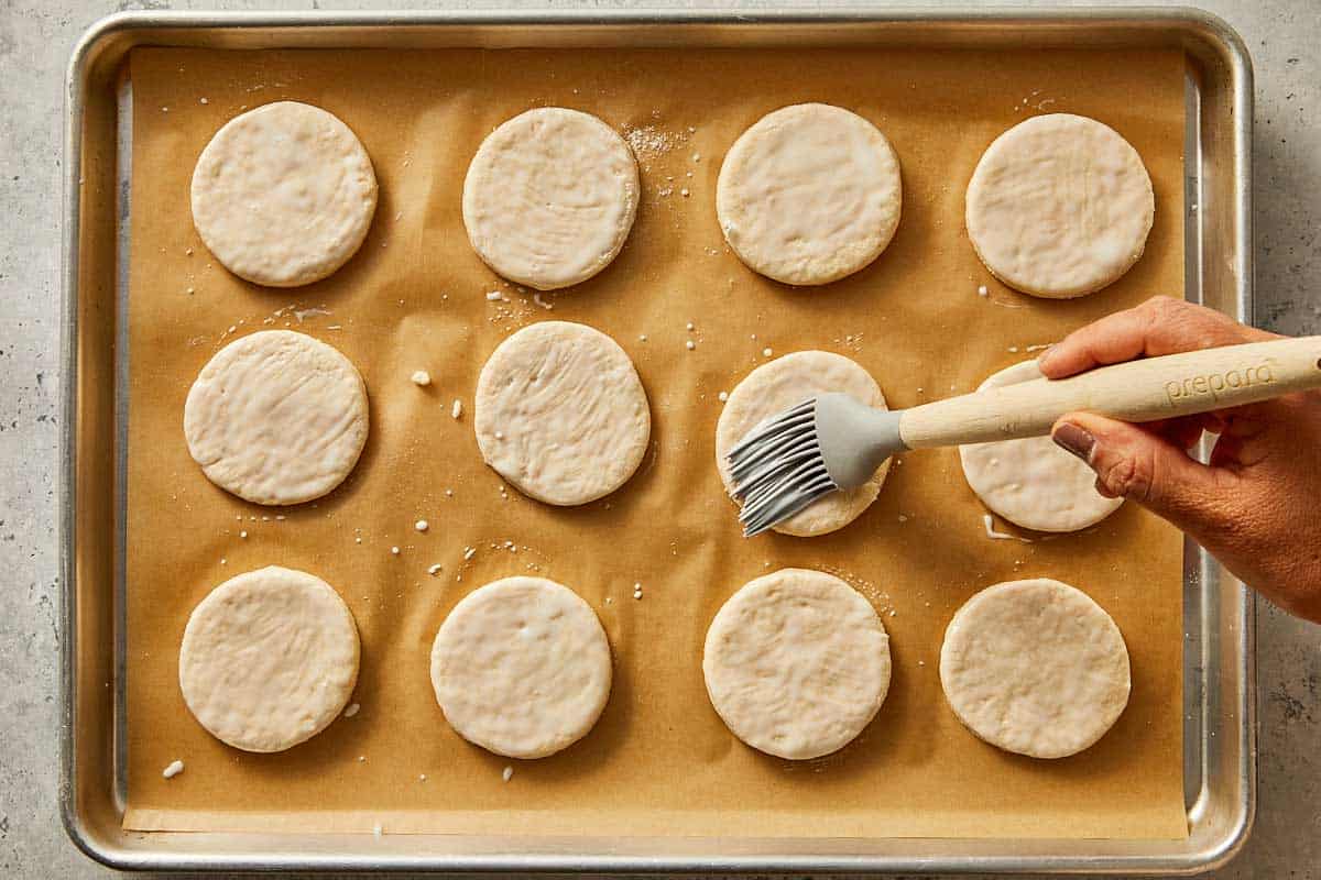 Round pieces of dough being brushed with remain buttermilk | CafeDelites.com