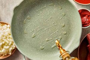 Olive oil heating in a large skillet for cabbage lasagna meat sauce.