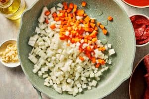 Chopped onion and carrot cooking in olive oil in a skillet.