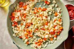 Garlic added to softened onion and carrot mixture in a skillet.