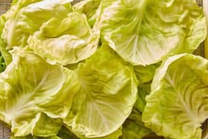 Softened cabbage leaves cooling on a wire rack after boiling.