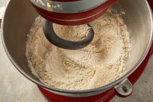 Yeast mixture foaming in a stand mixer bowl with warm milk and sugar