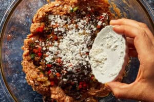 Adding white potato starch to the meat and vegetable mixture in a bowl.