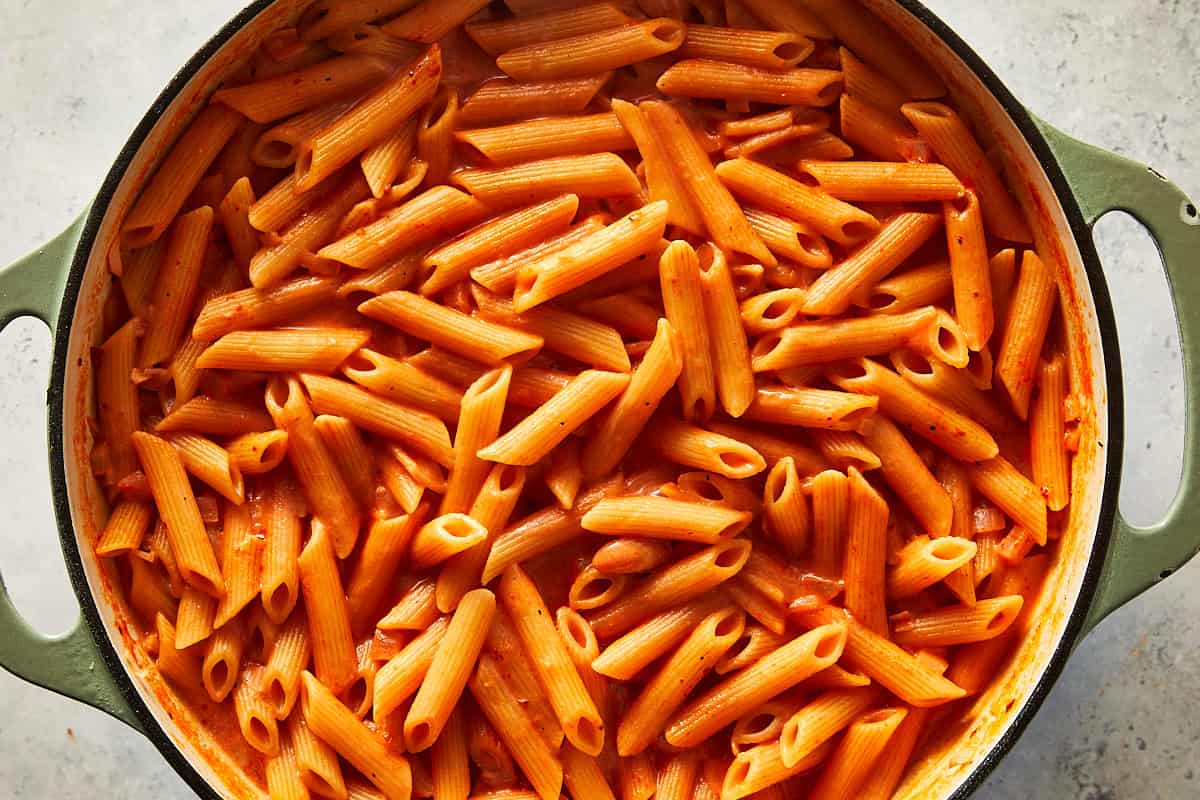 Cooked penne pasta fully coated in a thick spicy vodka sauce simmering in a single pot.