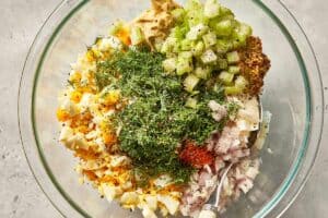 Mix of eggs, pickles, celery, shallot, green onions, parsley, tarragon, dill, mayonnaise, both mustards, vinegar, cayenne, and black pepper.
