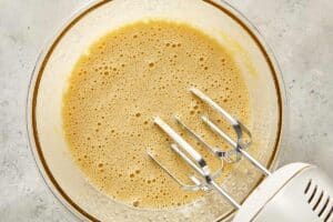 Electric hand mixer mixing the eggs and granulated sugar
