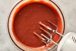 melted chocolate, vegetable oil, white vinegar, red paste being mixed