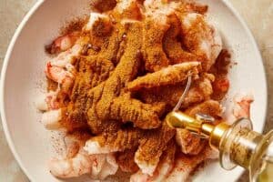 shrimp being tossed with cajun seasoning and olive oil