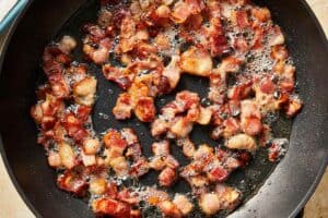Diced bacon in a pan being cooked until crispy