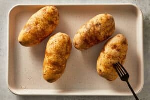 Potatoes being Poked with 4 to 6 holes in the potato with a fork