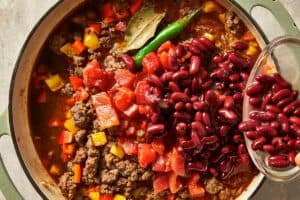 pouring beans into the beef with aromatics
