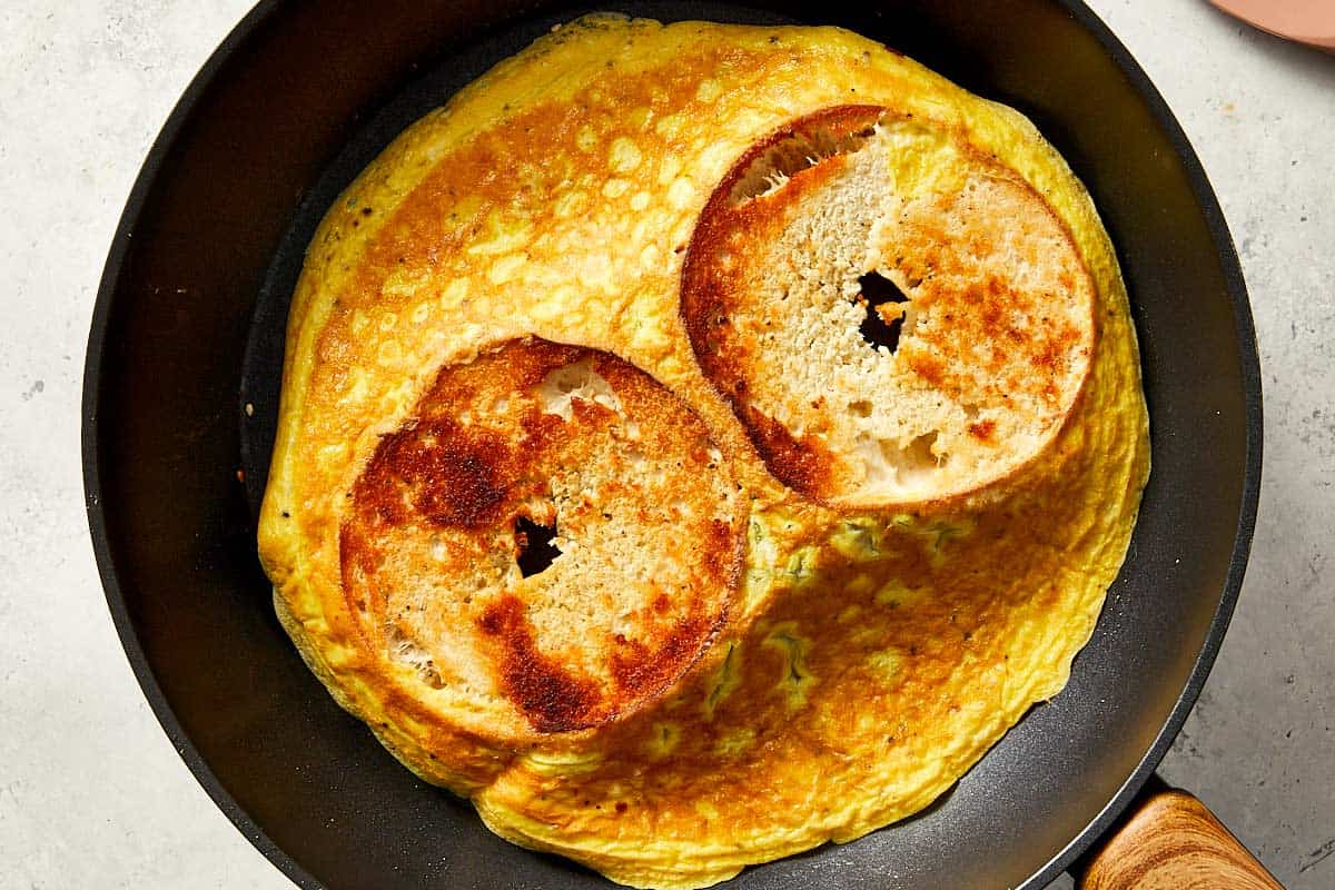 eggs and bagels being cooked in a pan