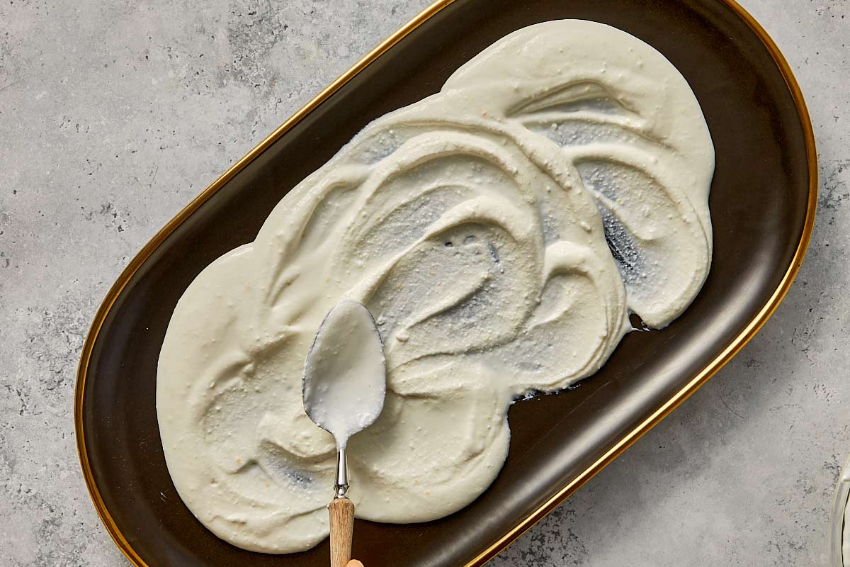 Whipped Feta being drizzle in a baking sheet