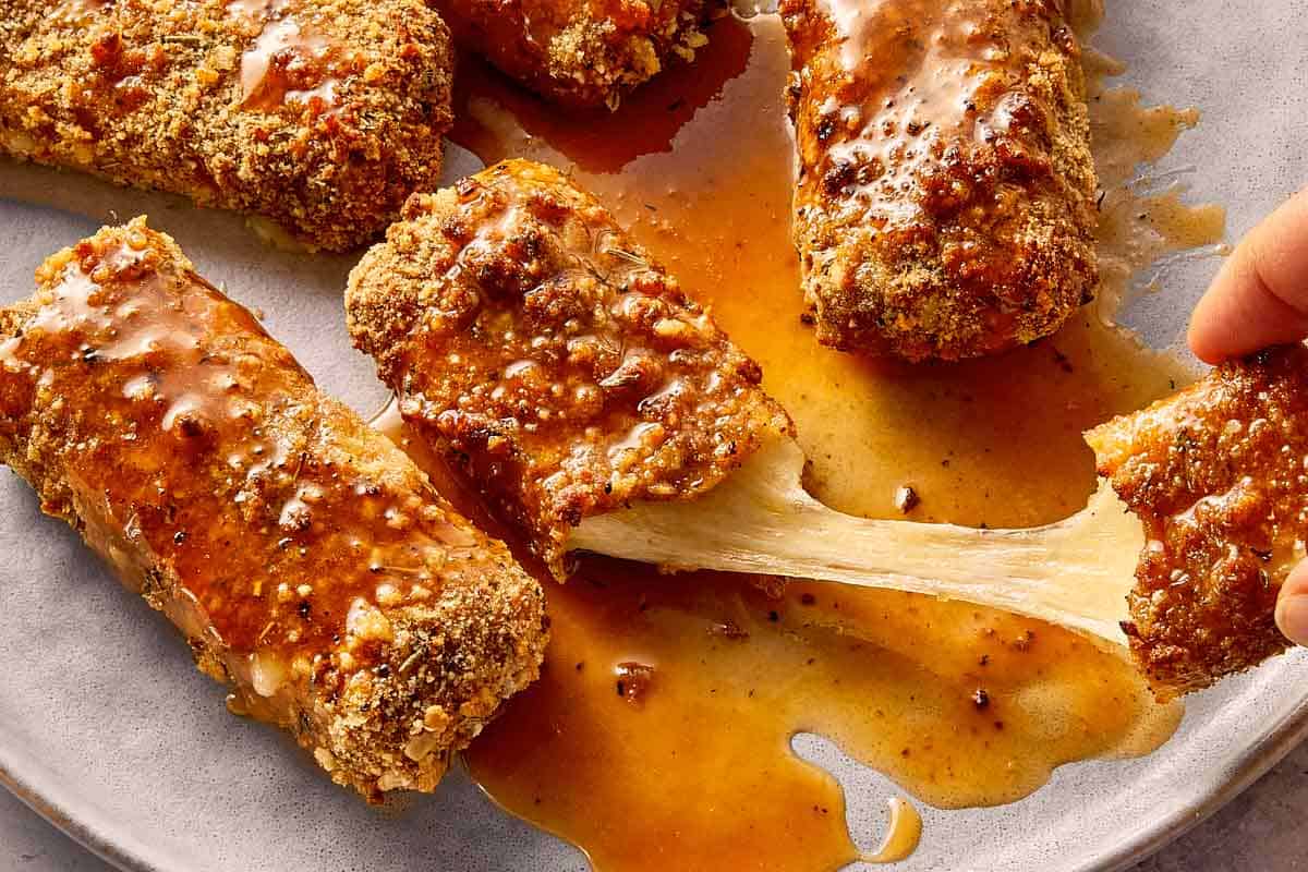 Pulling the cheese of mozarella sticks ready to eat and covered with hot honey sauce