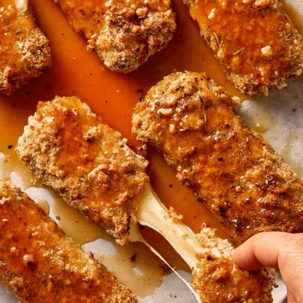 Pulling the cheese of mozarella sticks ready to eat and covered with hot honey sauce