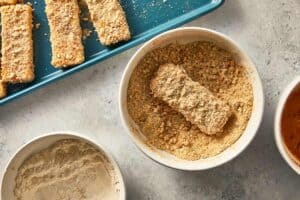 Mozzarella stick being coat a second time in the breadcrumbs