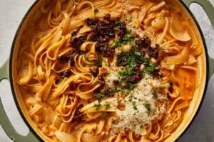 adding chili oil to the cooked pasta